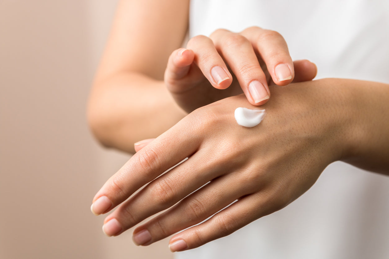 A woman using hand cream on her left hand.